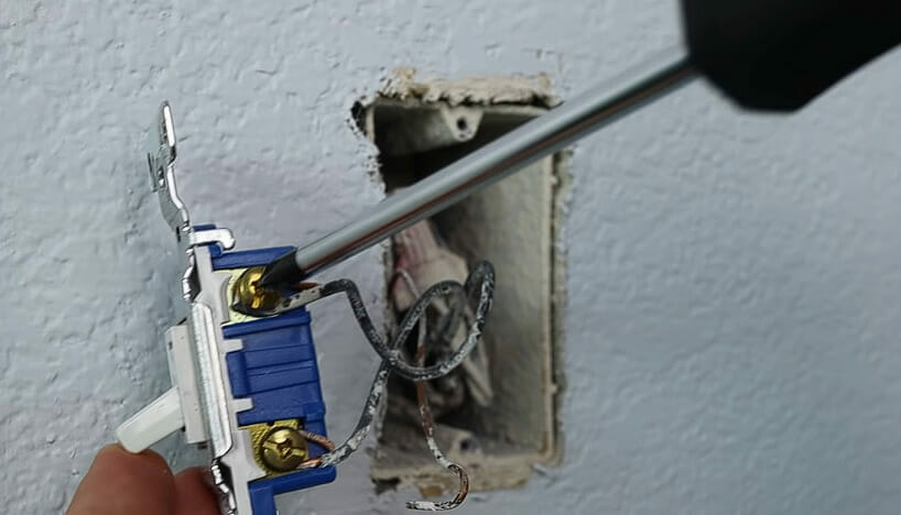 A man screwing a single pole light switch