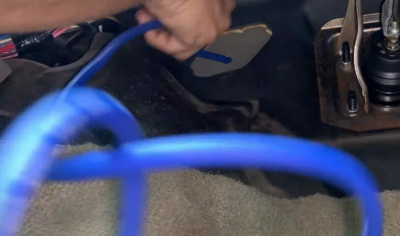 A person connecting the blue speaker wires to the mounted speaker