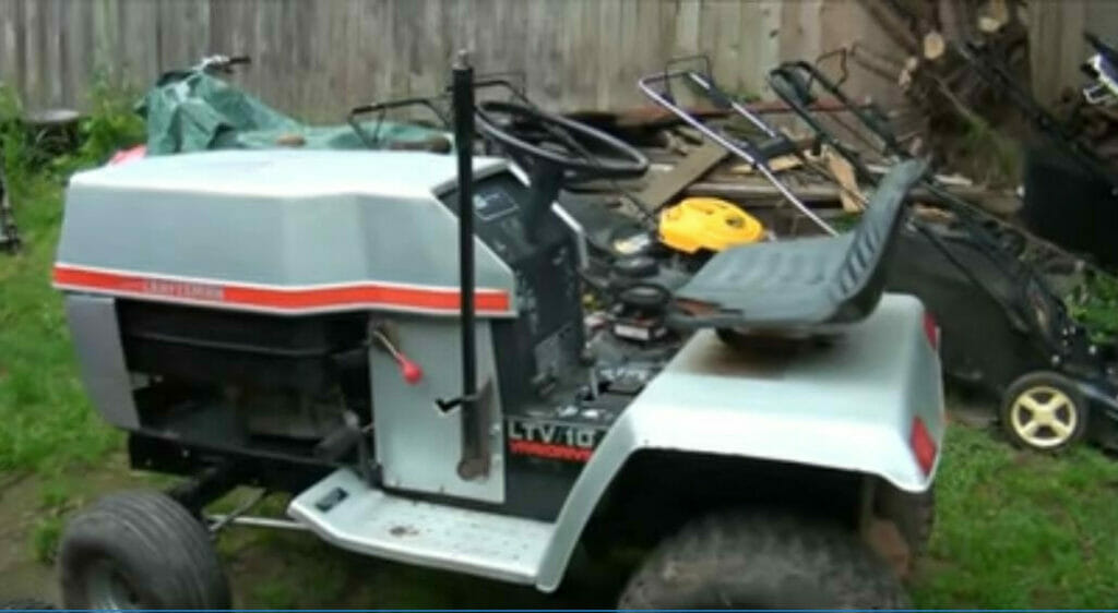 A small lawn mower is parked in a backyard