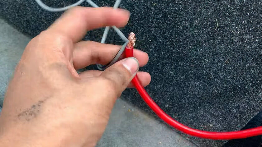 A person holding a stripped red color speaker wire