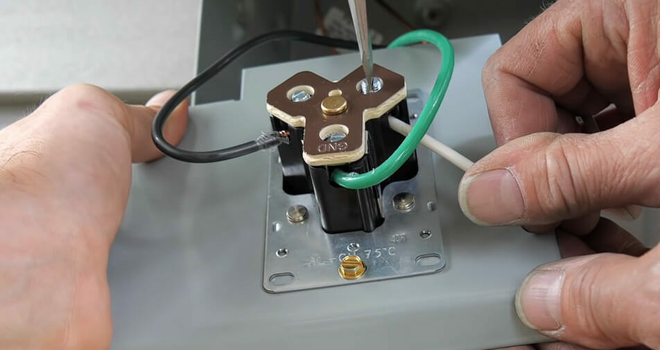 A person is inserting a black and green wire into a plug