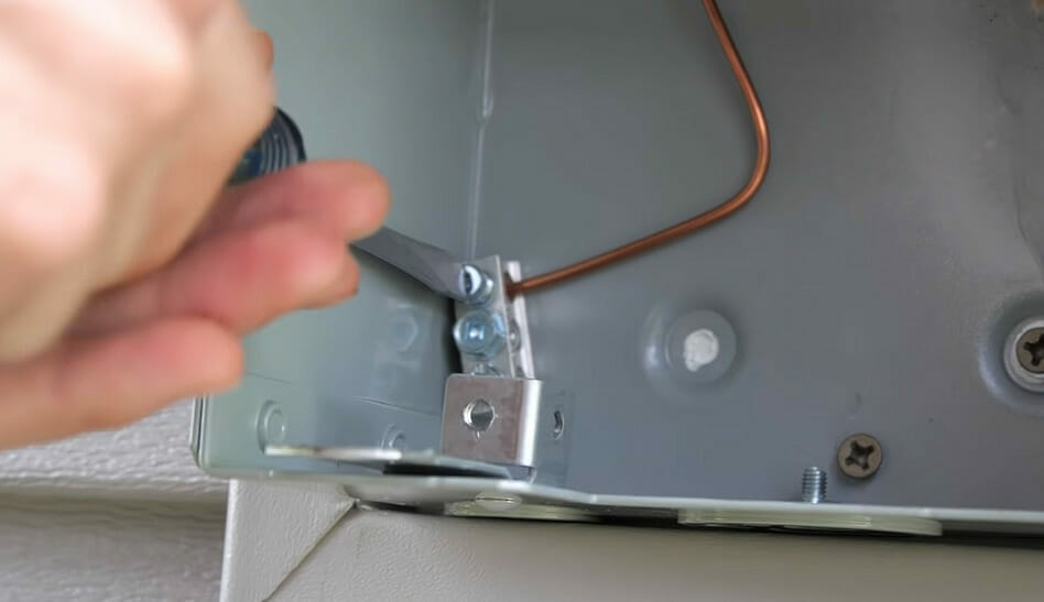 A person is securing a wire from a metal box 