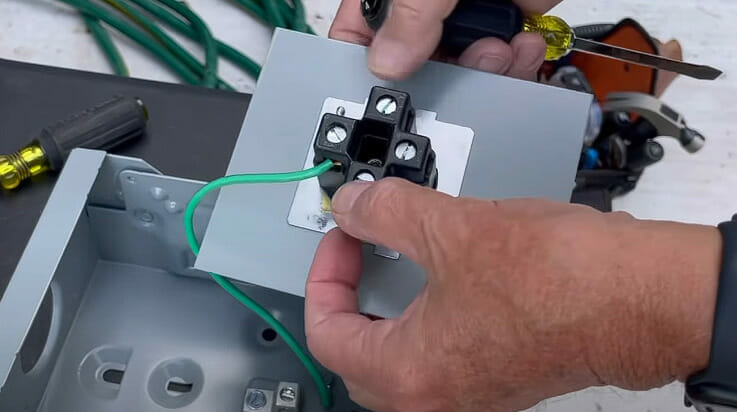 A person wiring a terminal with green wire