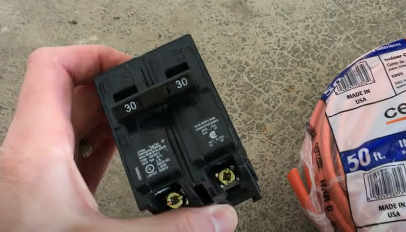 A person holding a circuit breaker beside a pack of wire