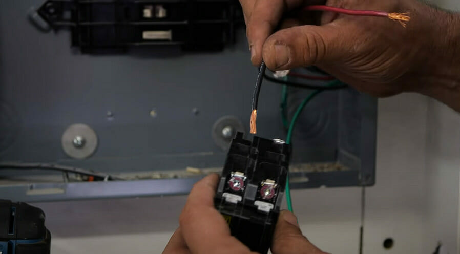 A person inserting wires to circuit breaker terminal