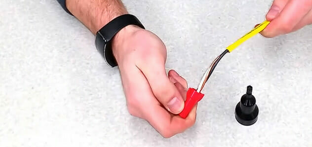 A person is capping off a wire in a red wire nut