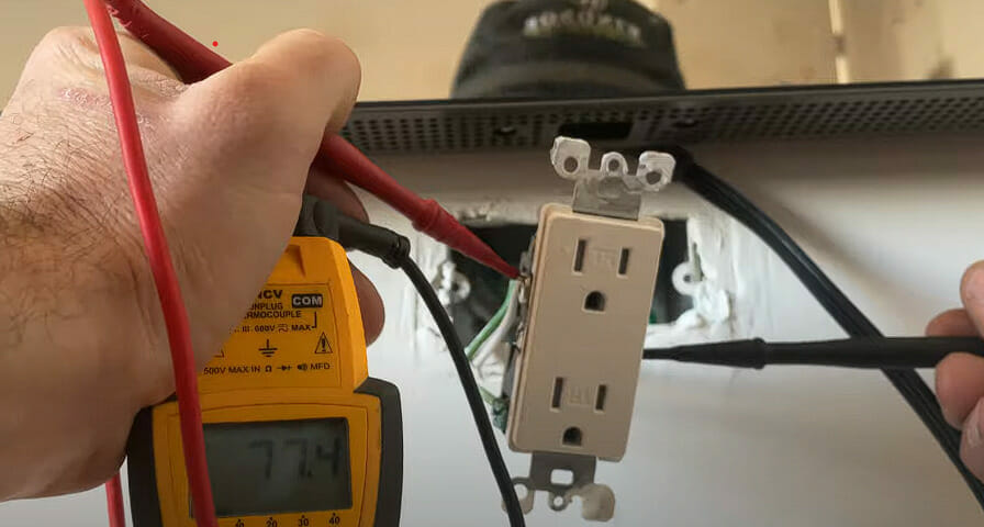 A person is using a multimeter to check an outlet