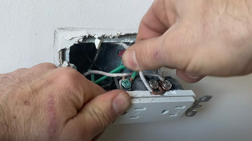 A person removing the ground wire on the broken switch