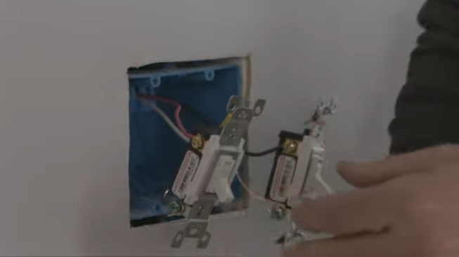 A man is installing a light switch in a wall