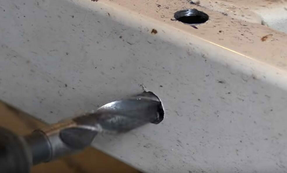 A person is using a drill screw to dig a hole on metal