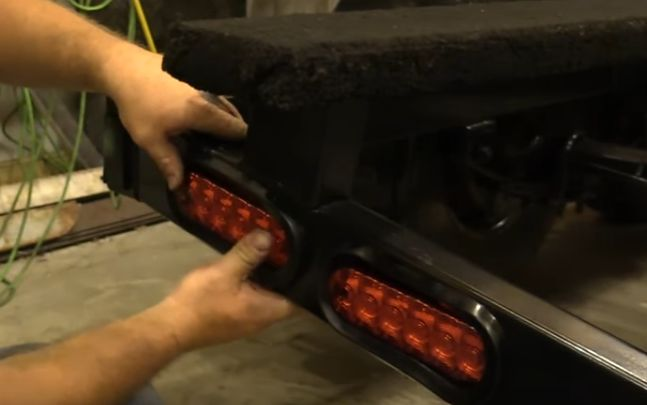 A man is working on a trailer with a red light on it