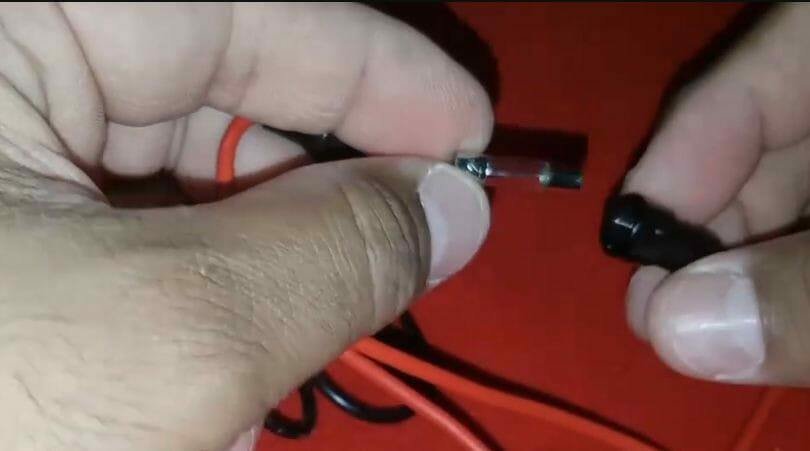 A person is holding a red wire and a black wire