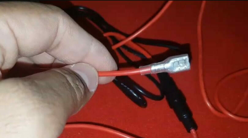 A person is holding a red wire and a red wire