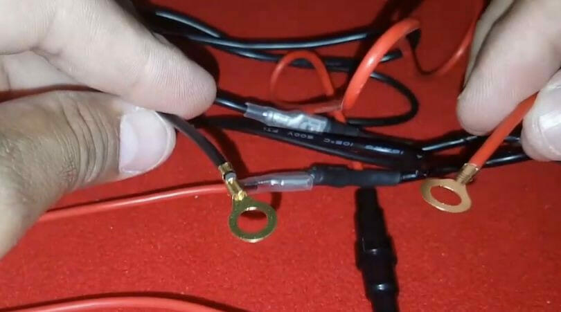 A person is putting wires together on a red table