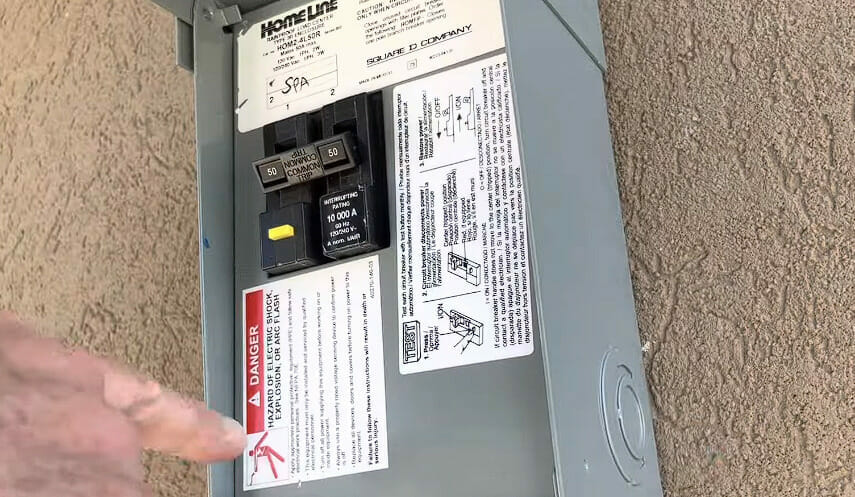 A person pointing the Caution Warning label on the circuit panel