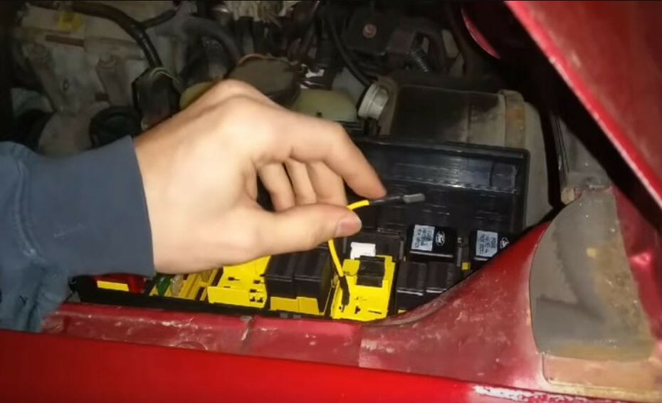 A person is holding a yellow wire to connect to a car relay