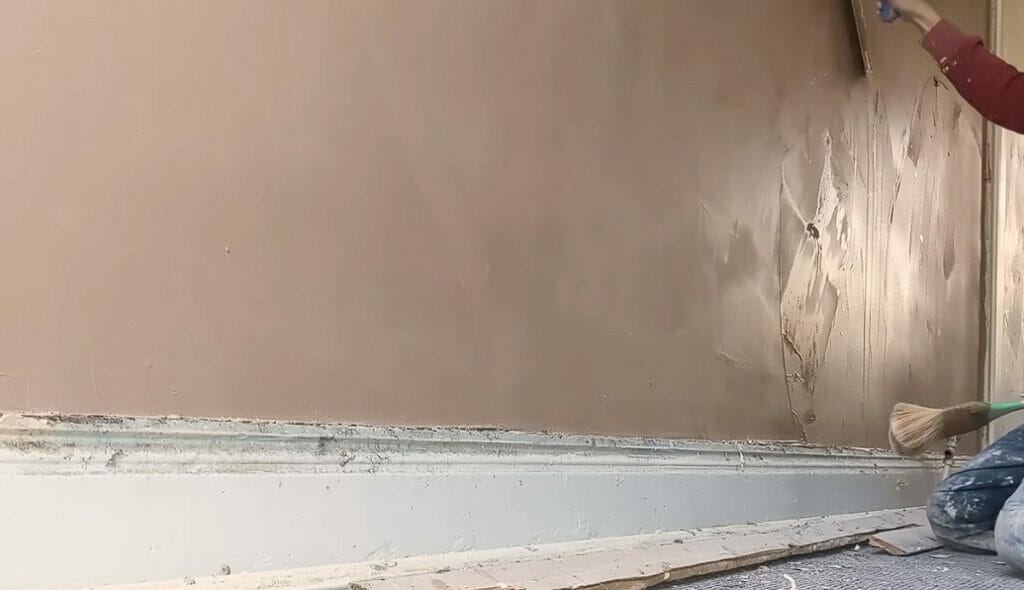 A person applying a coated plaster wall