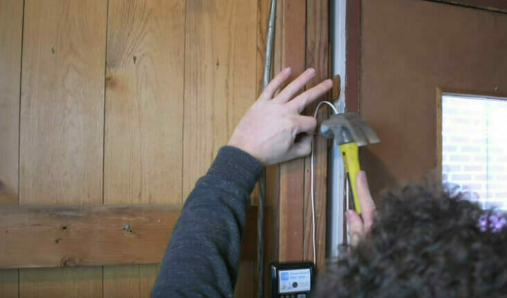 A person using a hammer to secure wire
