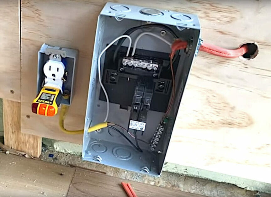 An undone outlet besides a breaker box