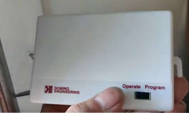 A person holding a small white box with the words operate and program