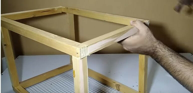 A man making the wood frame of the bird cage