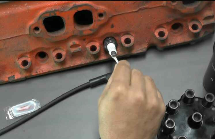 A person is installing spark plug wire heat shields onto a cylinder head