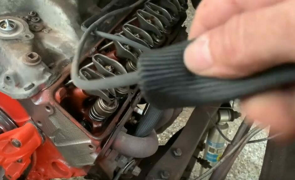 A person is installing spark plug wire heat shields on the engine of a car