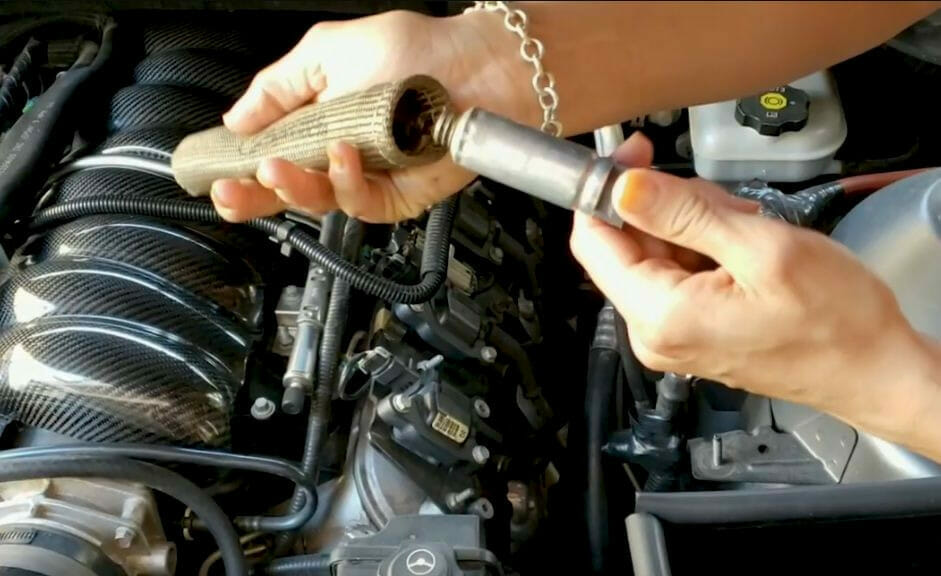 A person is installing spark plug wire heat shields on a car's engine