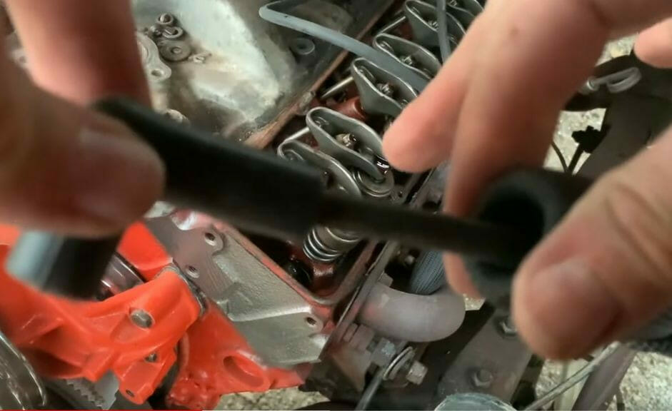 A person is installing spark plug wire heat shields on a car engine