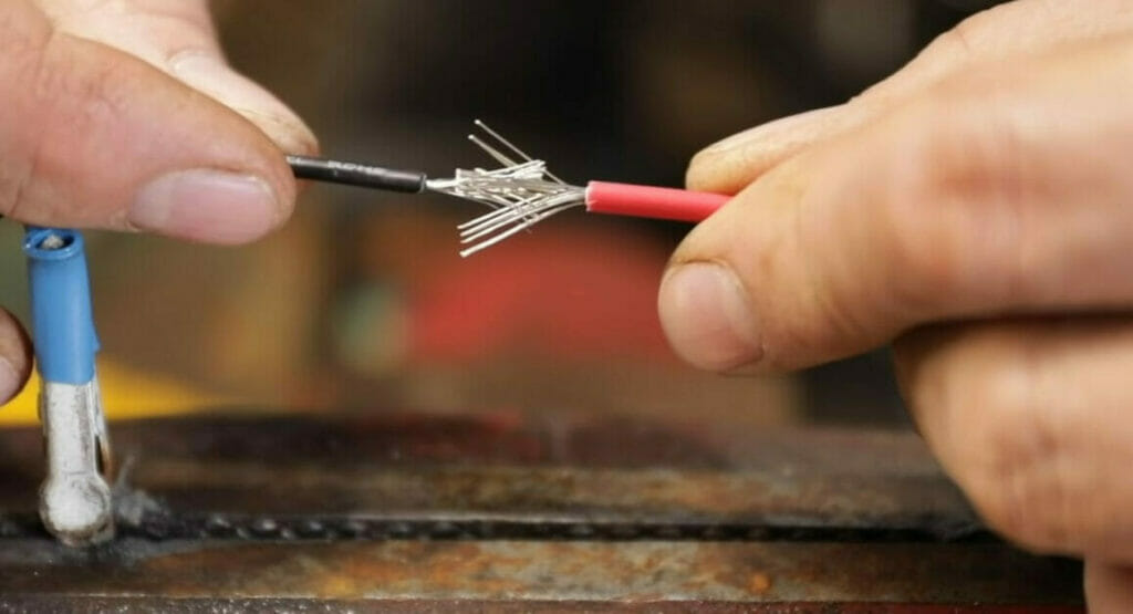 A person is repairing a chewed wire on a piece of metal