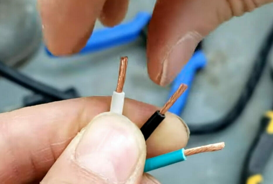A person holding a different color of stripped wires