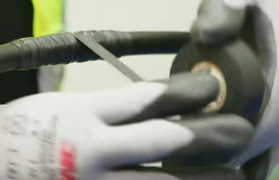 A person wearing gloves is holding a rubber hose to fix a chewed wire