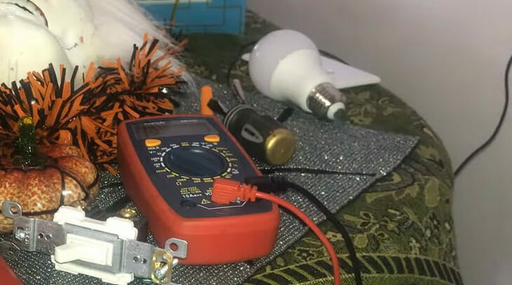 A multimeter sits on a table next to other electrical tools