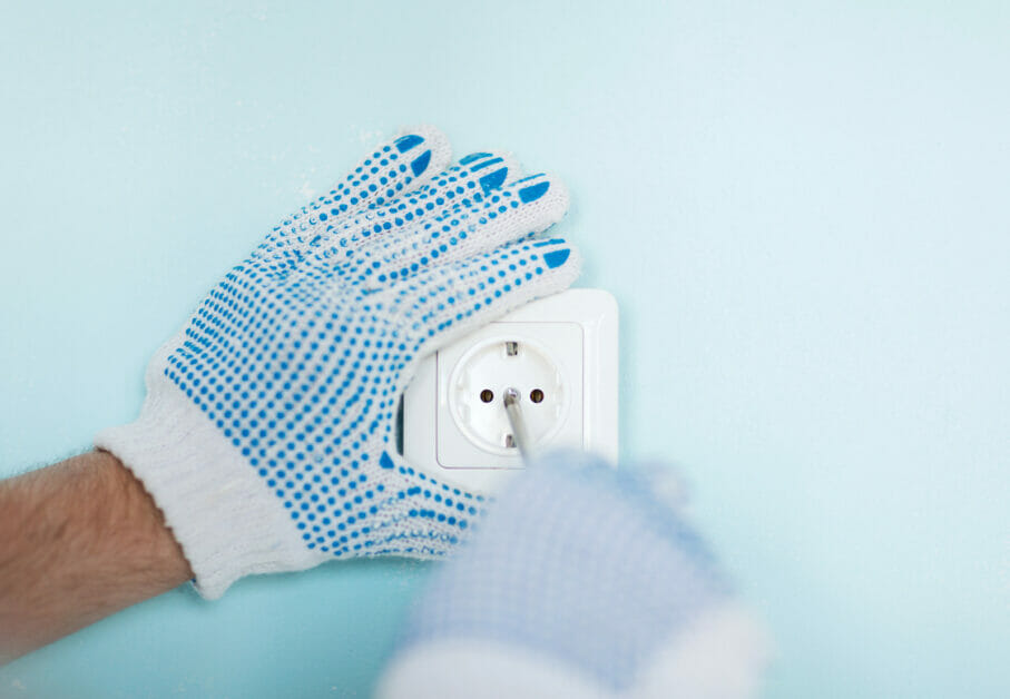 A man with blue gloves wiring a single pole light switch