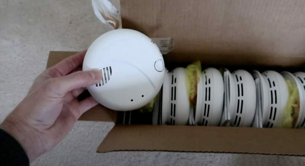 A person unboxing hard-wired smoke detectors