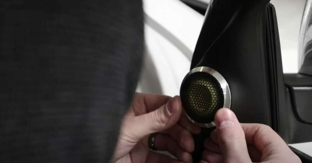 A person is installing a button on the door handle of a car.