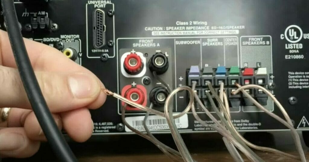 A person is connecting positive speaker wires