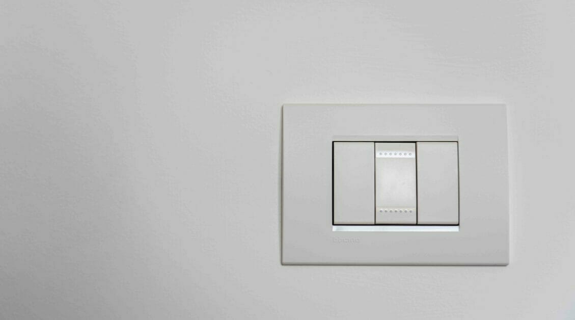 A white light switch on a white wall
