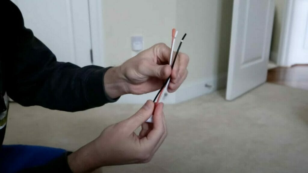 A man is holding a smoke detector wires