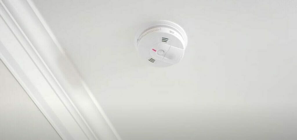 A hardwired smoke detector mounted on a room's ceiling