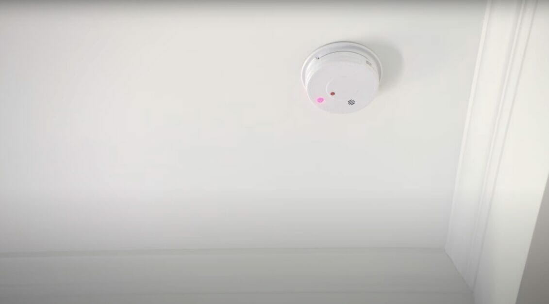 A white smoke detector in a white ceiling