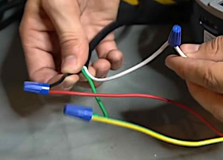 A person with blue, green, white and yellow capped wires