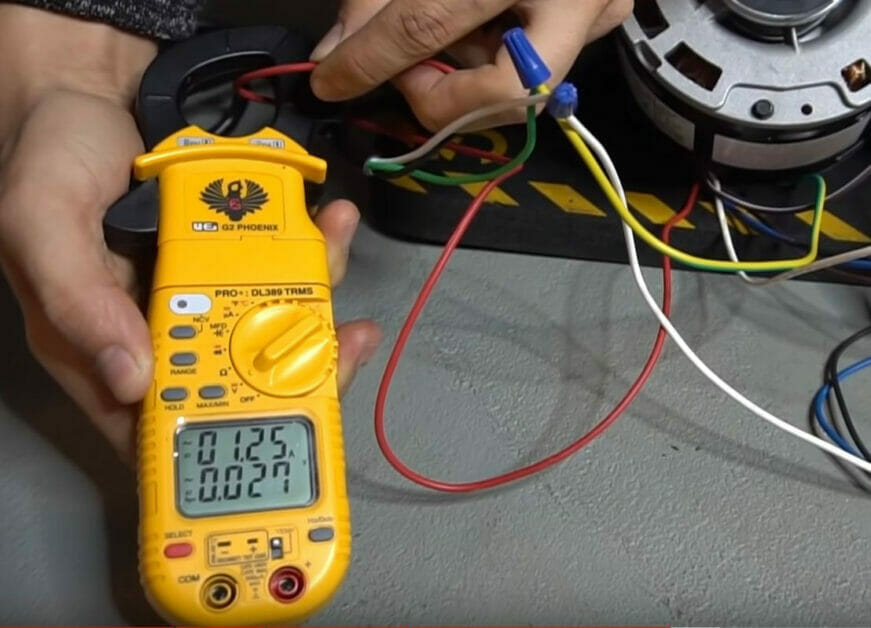 A person is using a multimeter to check the wiring of a motor
