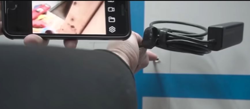 A person is using an endoscope to see the other side of the wall