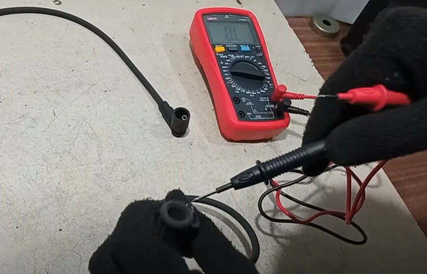 A person with black gloves setting up the multimeter