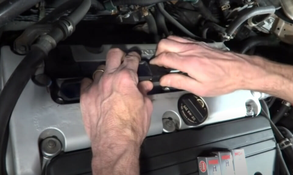 A person's hand accessing the spark plugs