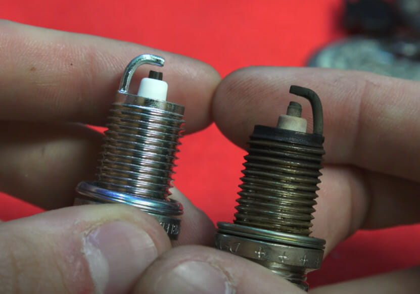 A person holding two spark plugs