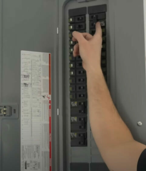 A person turning off a circuit breaker on the main panel
