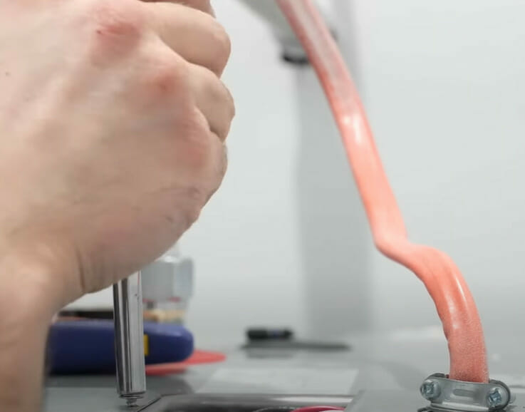 A person connecting wires to the red lead of a water heater