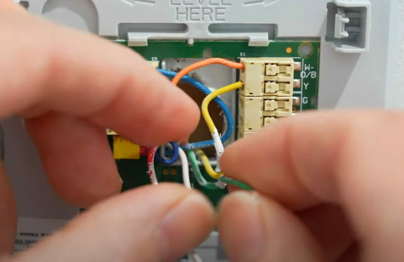 A person is wiring a Honeywell thermostat